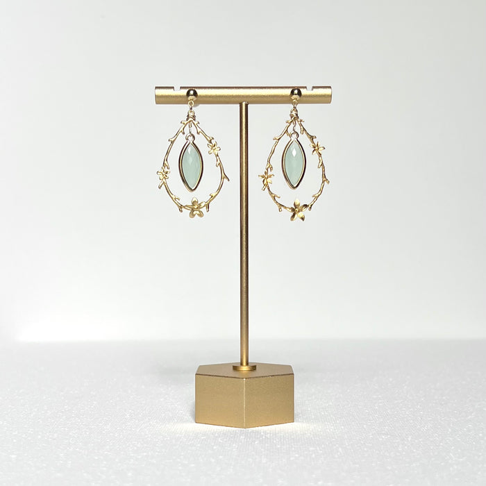 This earring set features a gold branch &amp; flower hoop in which hangs a minty green glass marquise shaped bezel set charm, hung on a gold filled 4mm ball stud earring post.&nbsp;