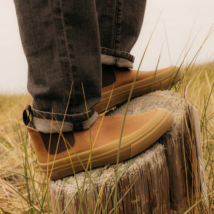 SeaVees Ballard Boot in tan leather with elastic side panels and durable gum sole, worn outdoors on wooden stump.