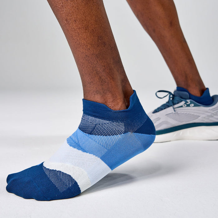 Feetures Elite Ultra Light No Show Tab socks in blue and white, worn by person in motion.