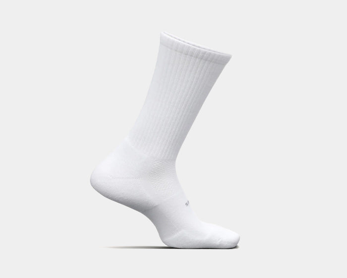 Feetures High Performance Max Cushion Crew socks in white with ribbed upper and cushioned sole, side view.