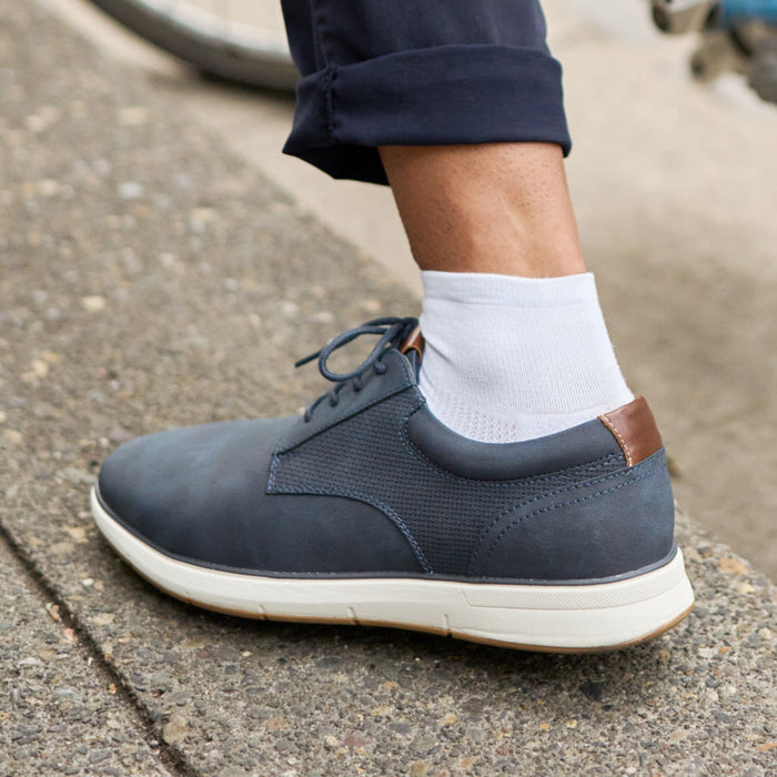 Feetures High Performance Max Cushion Quarter socks in white with moisture-wicking fabric worn with navy lace-up shoes, lifestyle context.