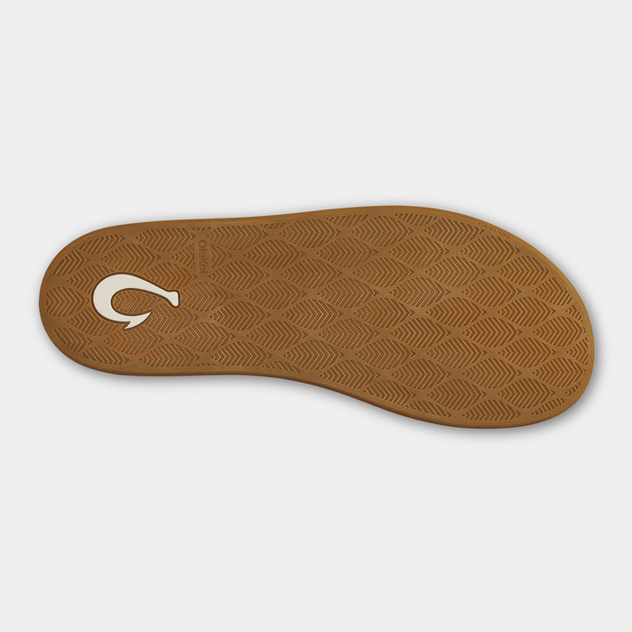 OluKai Ku'u sandal outsole in tan rubber with textured diamond pattern and white logo detail, bottom view.