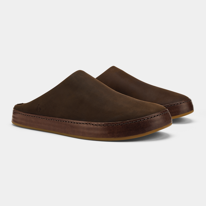 OluKai Ku'u slip-on shoes in rich brown leather with seamless stitching and a durable rubber sole, angled side-front view.
