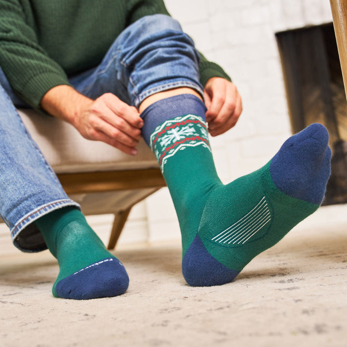Feetures Limited Edition "Evergreen" Everyday Max Cushion Crew socks in green with blue accents and festive pattern, lifestyle context.