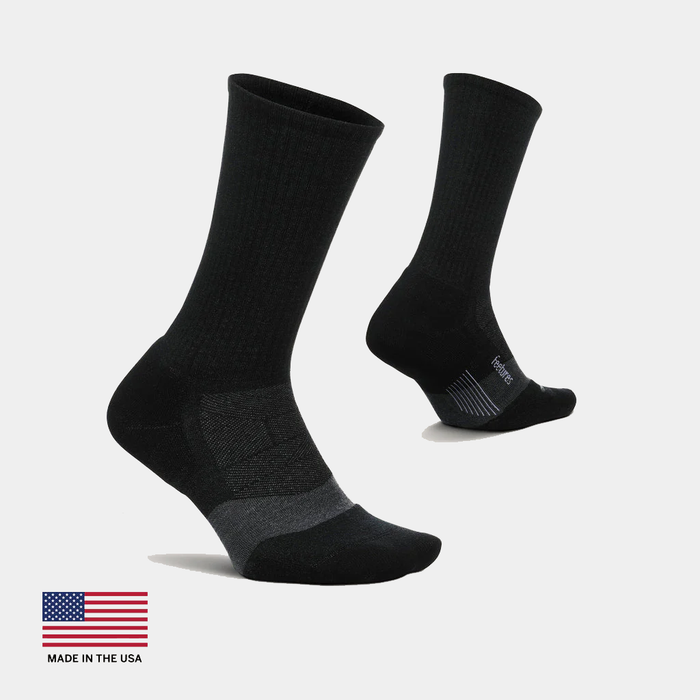 Feetures Merino 10 Max Cushion Crew socks in black with ribbed upper and reinforced heel and toe, side and angled views.