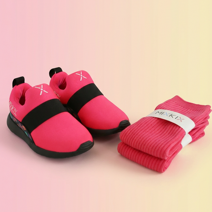 Pink children's shoes with black soles and matching socks on a gradient background