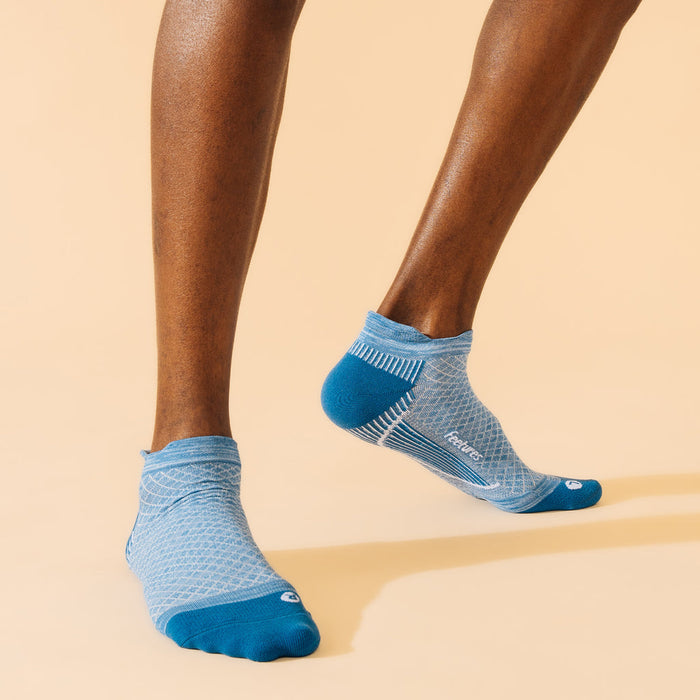 Feetures Plantar Fasciitis Relief Sock Light Cushion No Show Tab in light blue with supportive arch design, worn by person in motion.