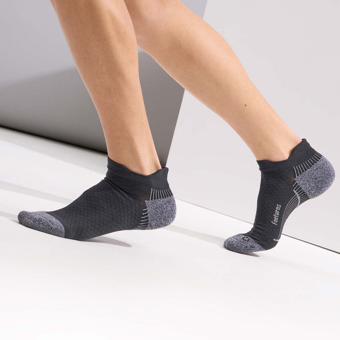 Feetures Plantar Fasciitis Relief Sock Light Cushion No Show Tab in black with gray cushioned heel and toe, worn during walking.