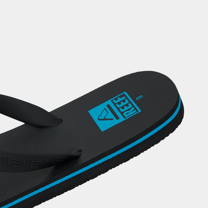 Reef Seaside flip-flops in black with blue logo and textured footbed, angled top view.